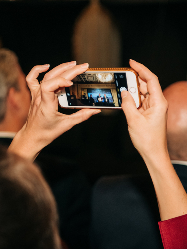 Person photographing award ceremony on stage with mobile phone