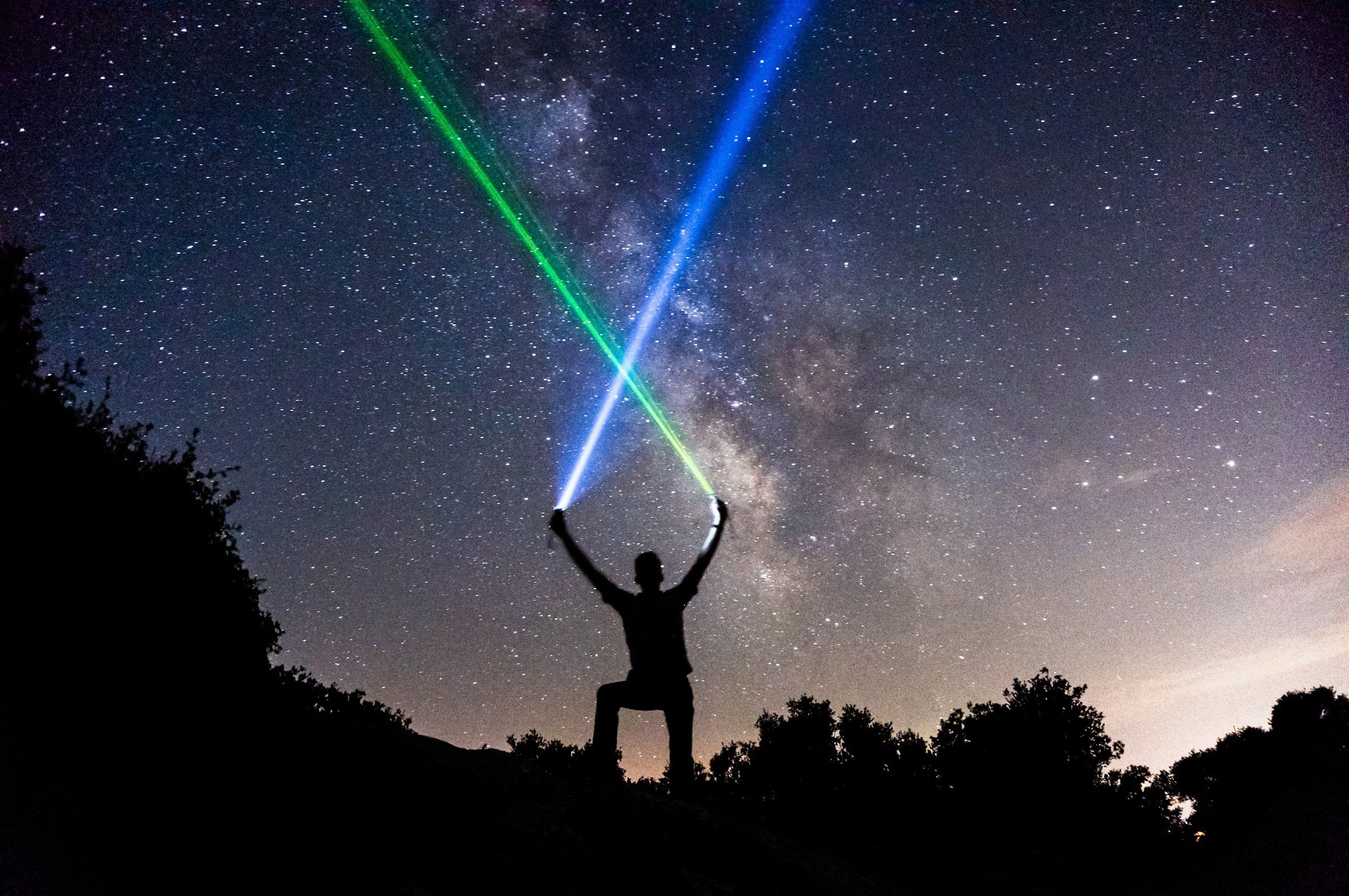 person korsar laserstrålar mot himmel